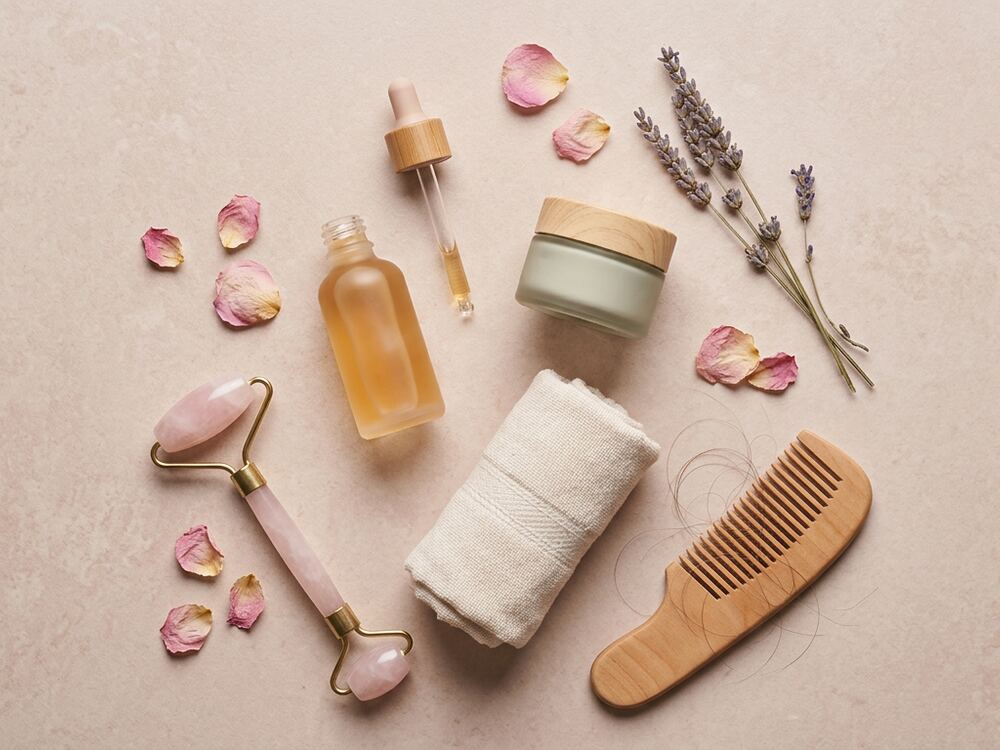 Serum bottle, cream jar, comb and rose petals