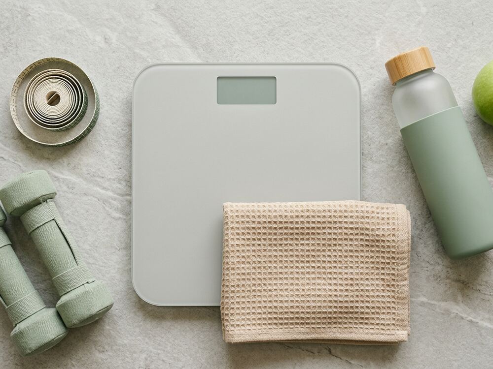 Scale, measuring tape and small dumbbells on stone